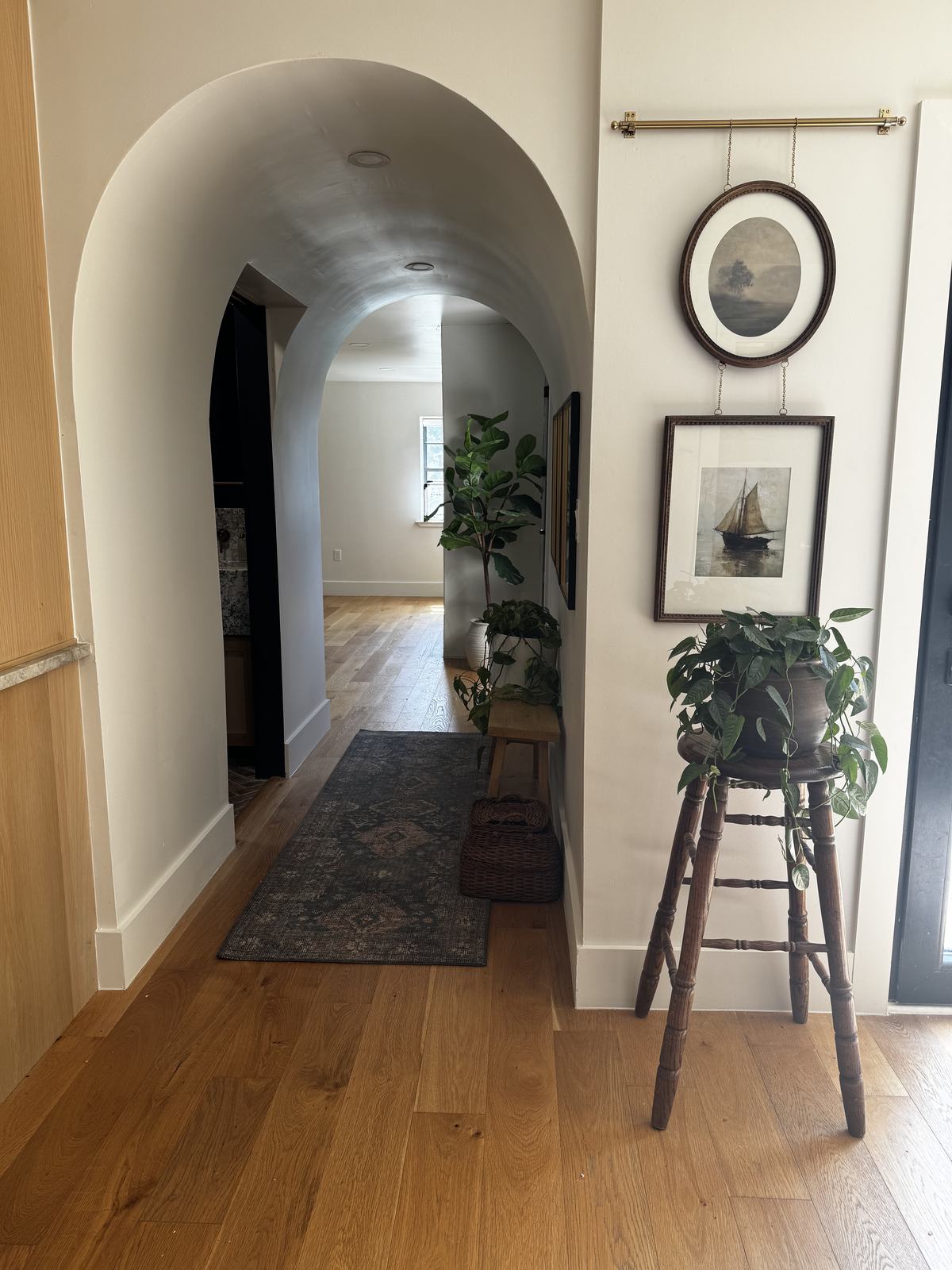 Plaster archway with vintage seascape paintings and wide plank oak floors