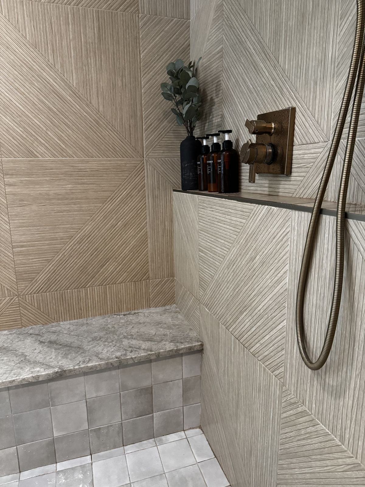 Shower with fluted geometric tile, stone bench and unlacquered brass fittings