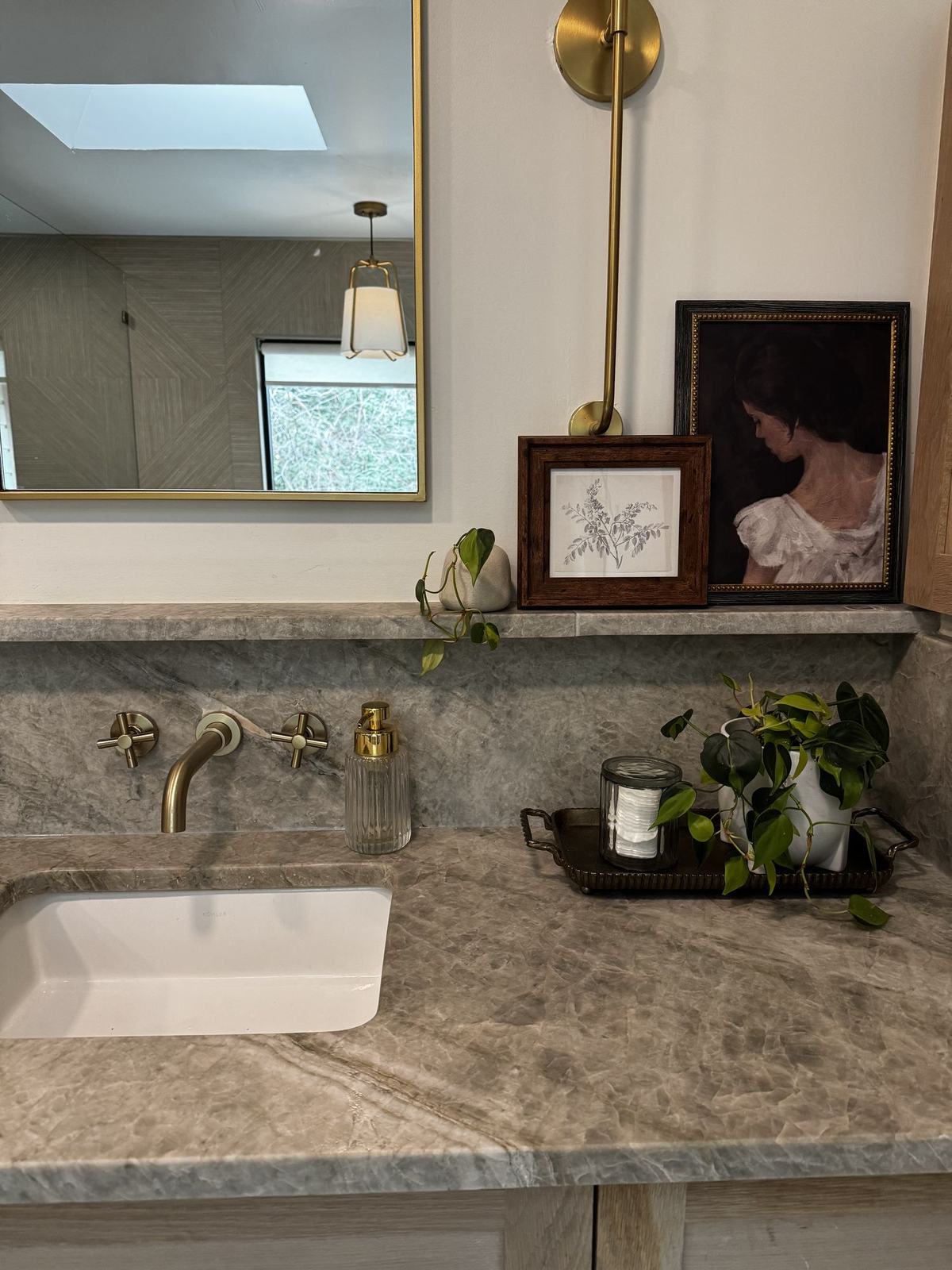 Bathroom vanity in quartzite with wall mounted brass taps and an antique portrait