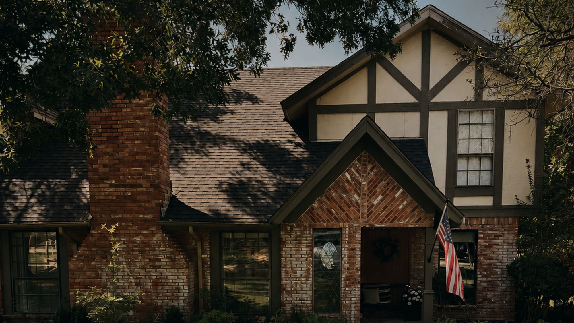 The front of the house in late afternoon light, brick and timber under a live oak