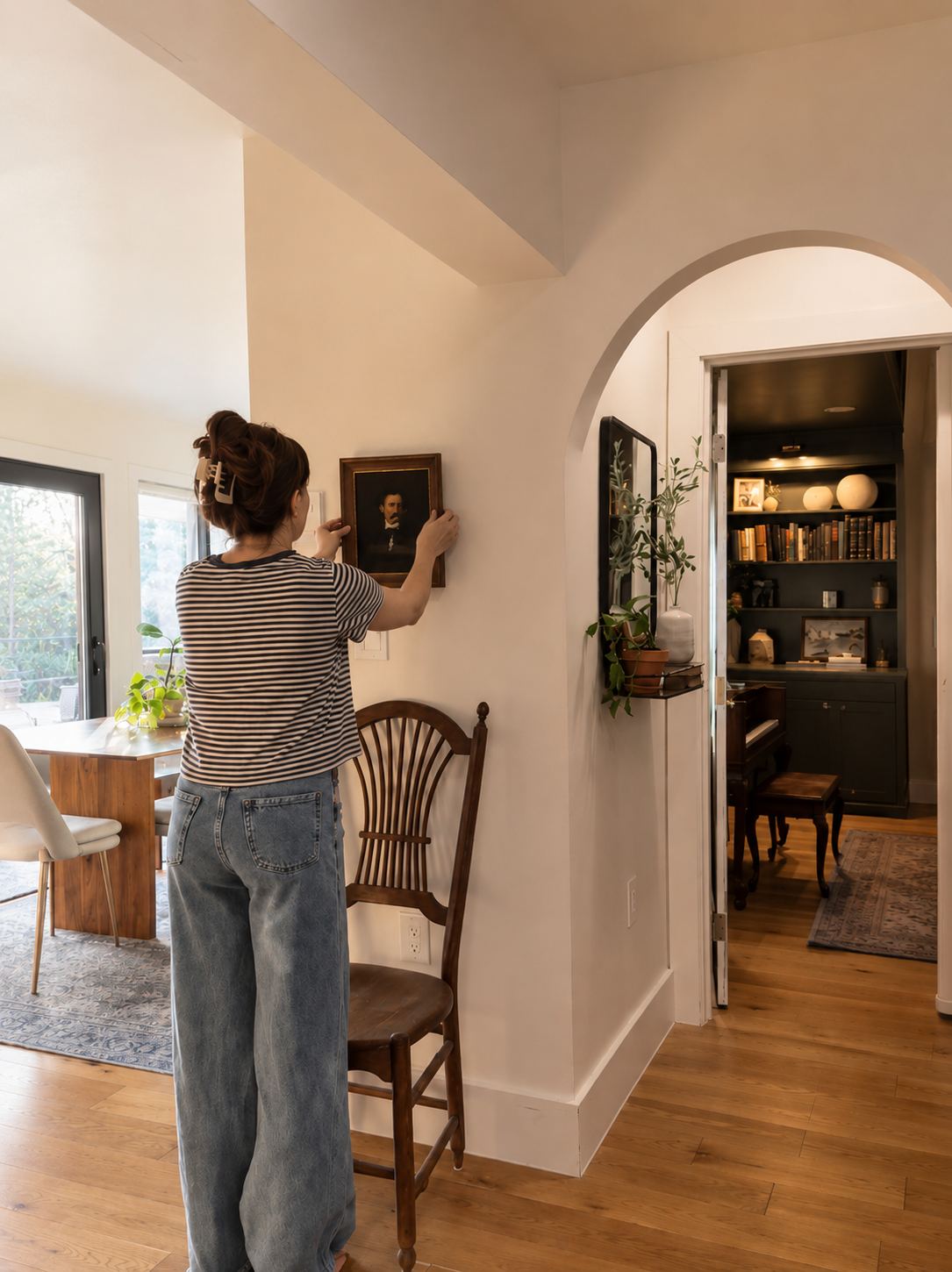 Shelby hanging a small antique portrait beside a plaster archway