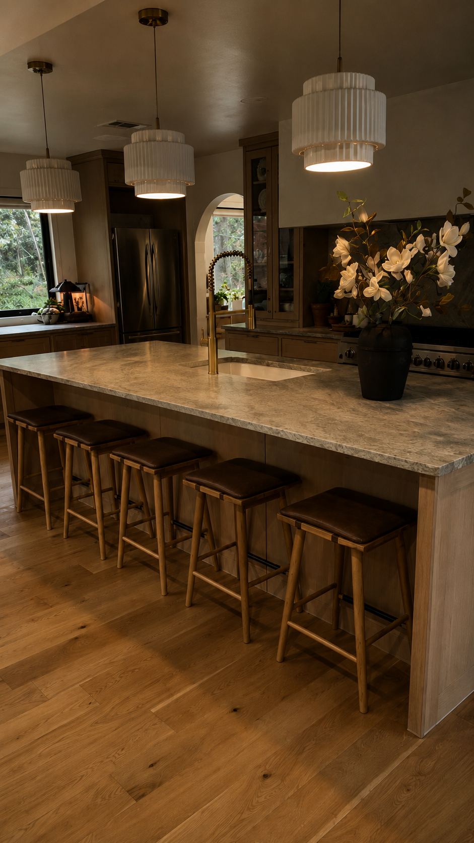 Kitchen island in honed stone with fluted pendants and leather stools